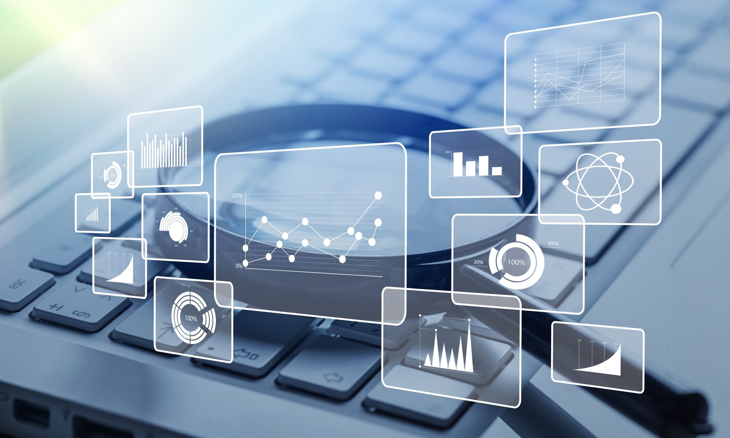 Magnifying glass on a computer keyboard with overlay of charts and graphs